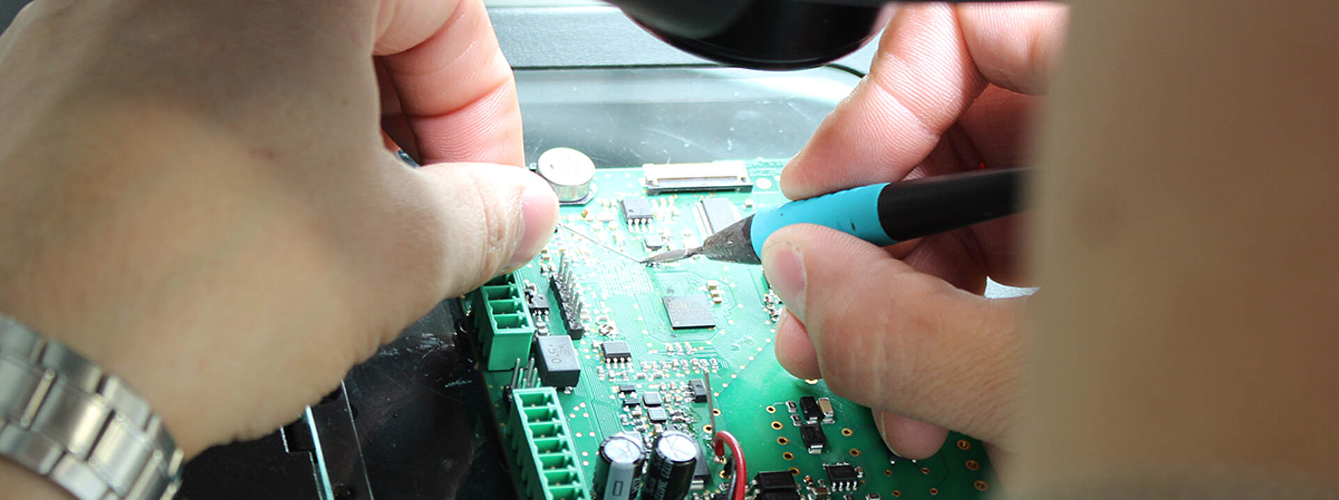 An employee repairing a device at a soldering station.