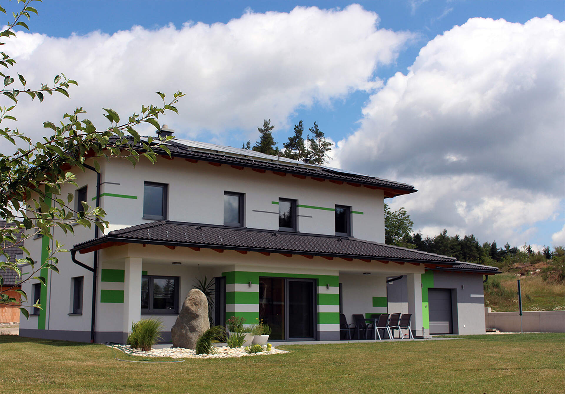 Einfamilienhaus mit Garten vor bewölktem Himmel